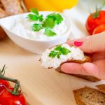 a person holding a piece of bread with cottage cheese on it